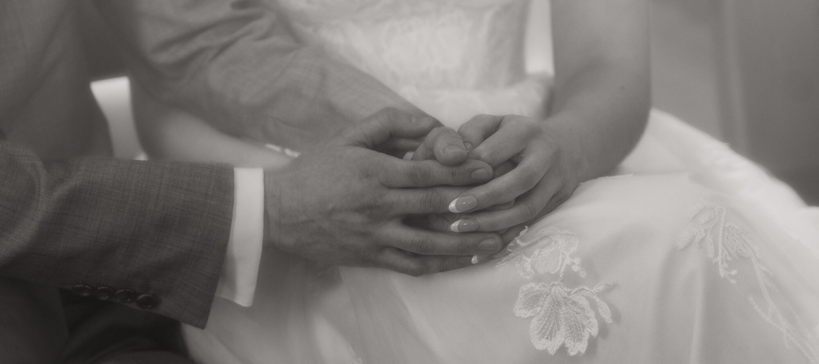 Bride and Groom close up of holding hands while they pray. Black and white image.