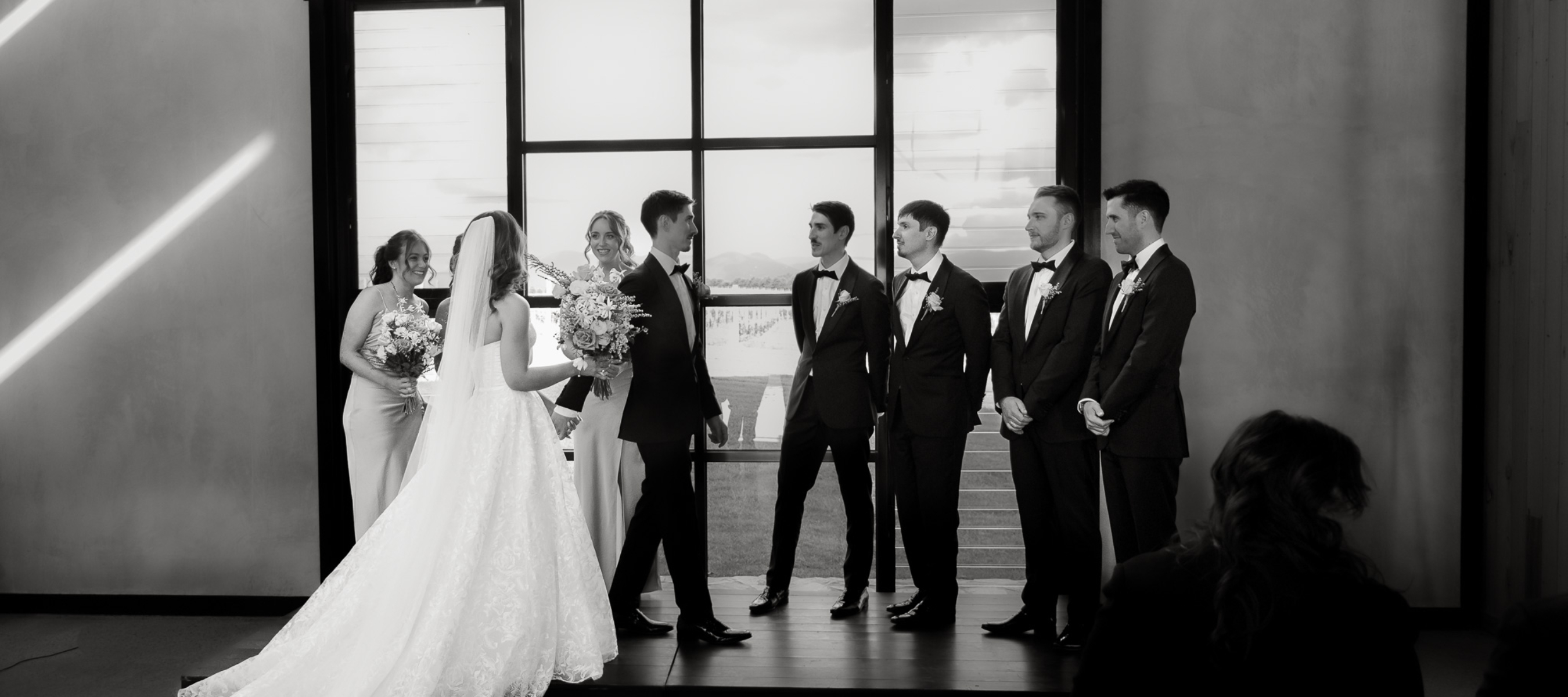Bride and Groom walking back to the alter at their wedding ceremony surrounded by their bridal party. Black and white image.